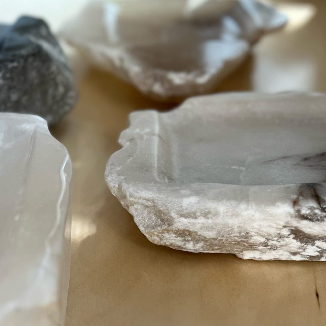 Angled close-up view: multiple alabaster stone trays, with a gray and white tray in focus.
