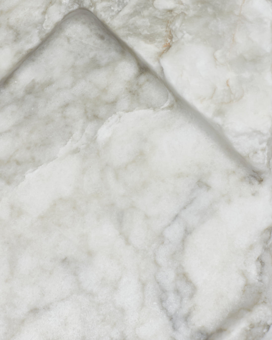 Top-down close-up: light gray-green alabaster surface, gray streaks, light veining, beige flecks.
