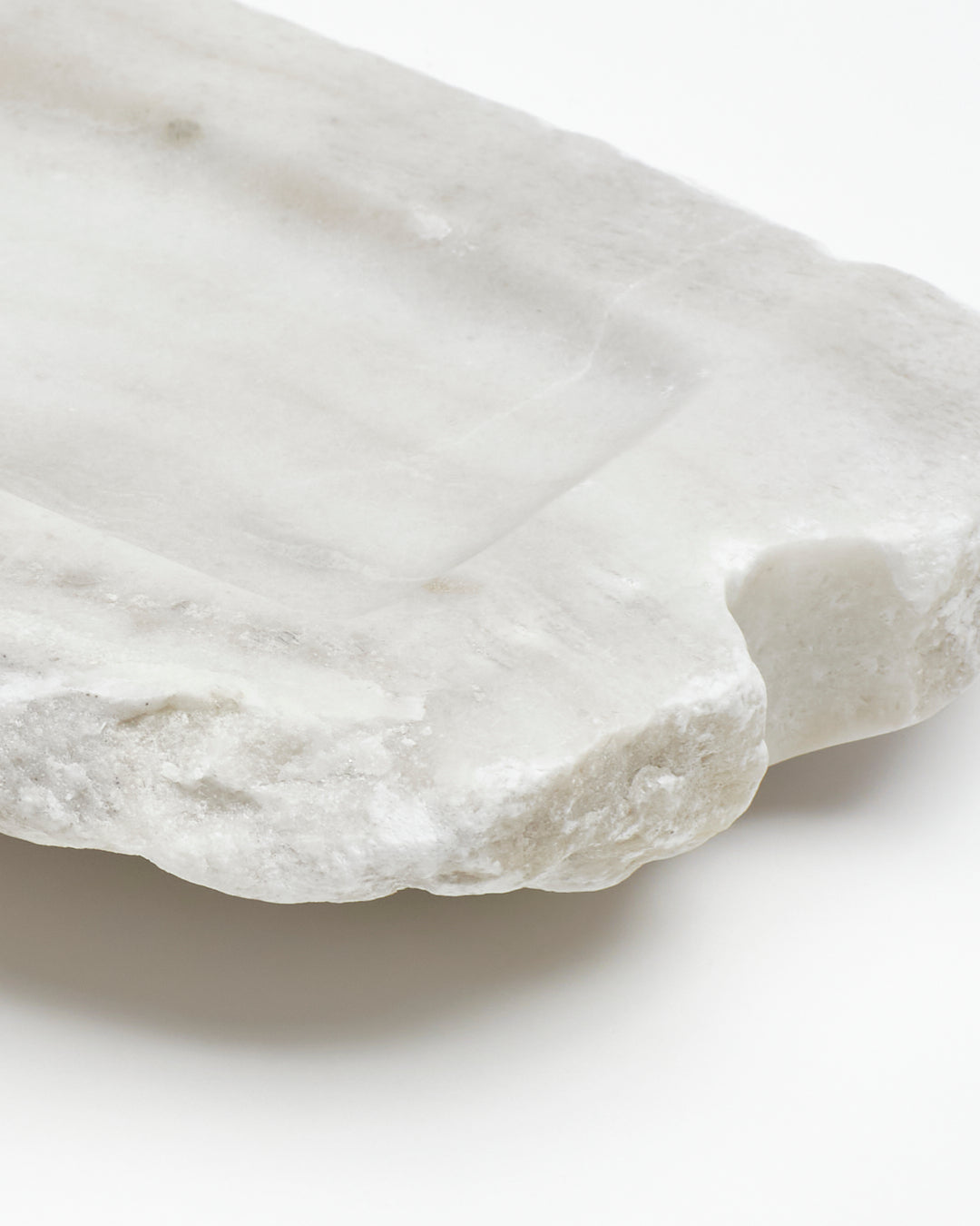 Angled back close-up: off-white alabaster tray with raw edges, subtle marks, semicircle cutout.