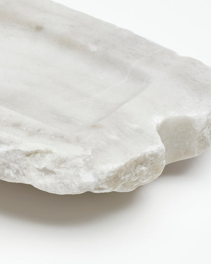 Angled back close-up: off-white alabaster tray with raw edges, subtle marks, semicircle cutout.