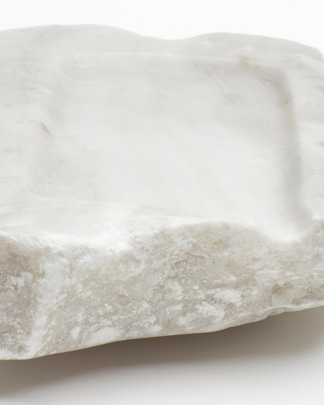 Front-on close-up: off-white alabaster sculpture with raw edges and subtle marks.