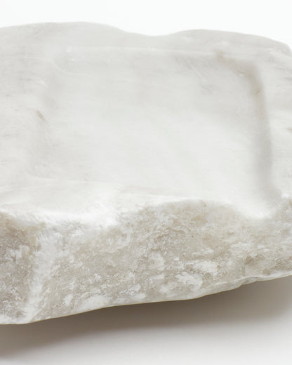 Front-on close-up: off-white alabaster sculpture with raw edges and subtle marks.