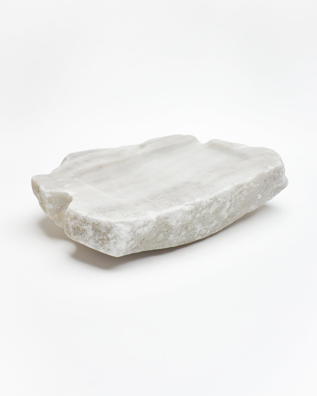 Angled back: organic-rectangle off-white alabaster tray with raw edges, flecks, semicircle cutout.