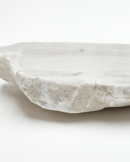 Close-up side view: off-white alabaster sculpture with raw edges, subtle marks, and flecks.