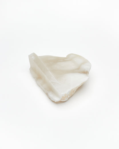Angled back view: white translucent alabaster tray with brown flecks, raw and smooth edges.