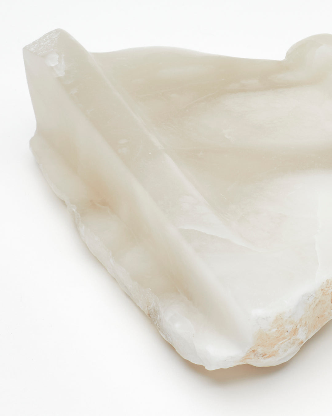 Angled back close-up: white translucent alabaster tray with brown flecks, raw and smooth edges.