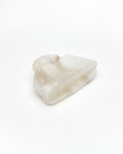 Angled view: white translucent alabaster tray with raw and smooth edges.