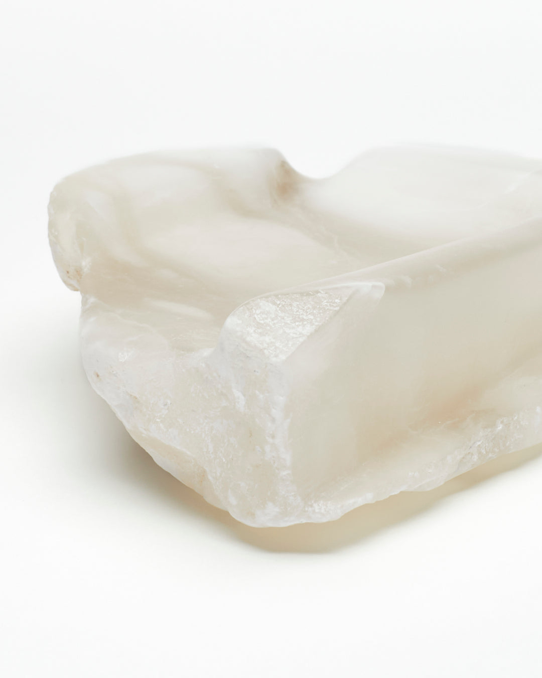 Front-corner close-up: white translucent alabaster tray with raw and smooth edges.