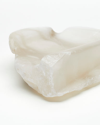 Front-corner close-up: white translucent alabaster tray with raw and smooth edges.