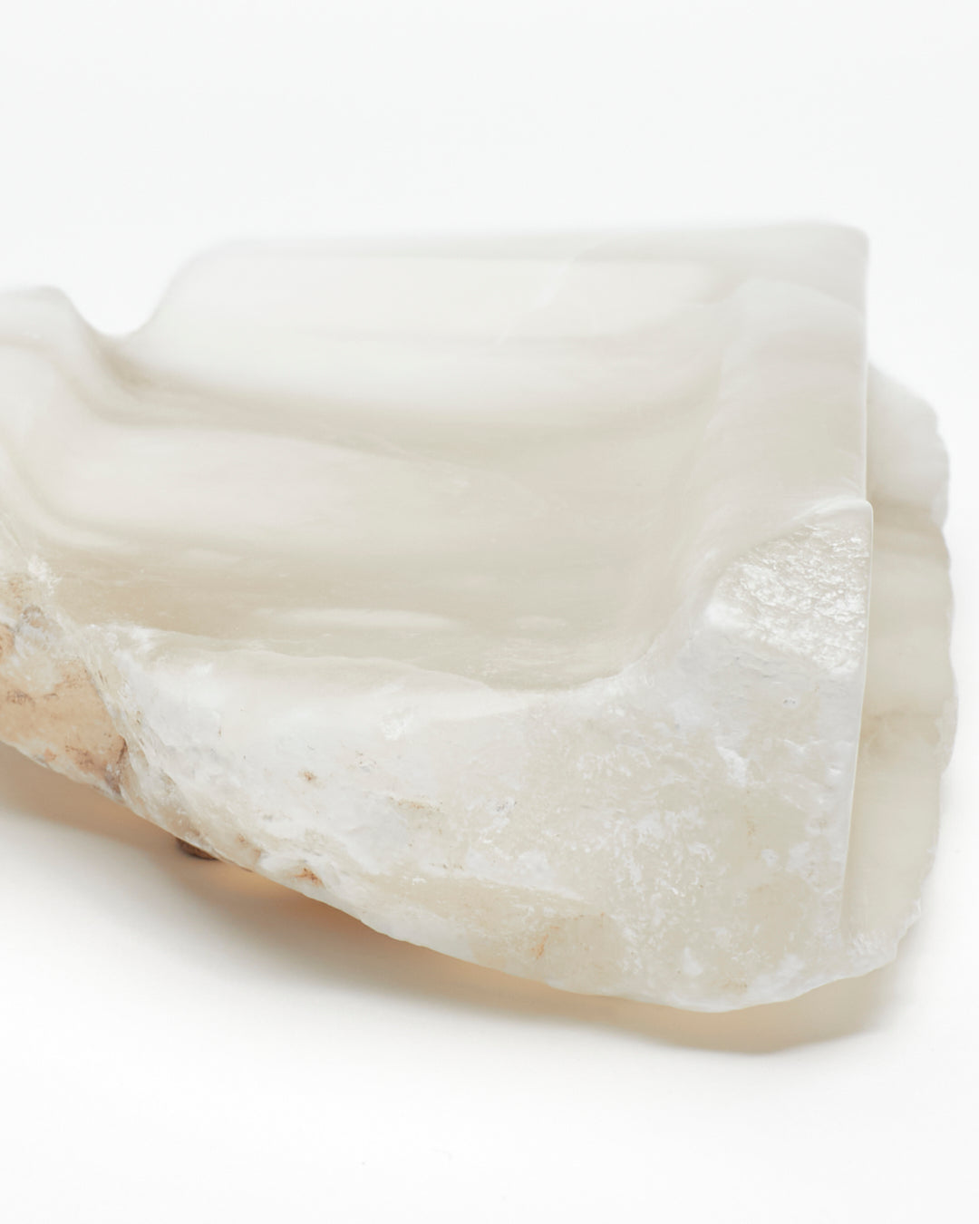 Front-on close-up: white translucent alabaster tray with brown flecks, raw and smooth edges.