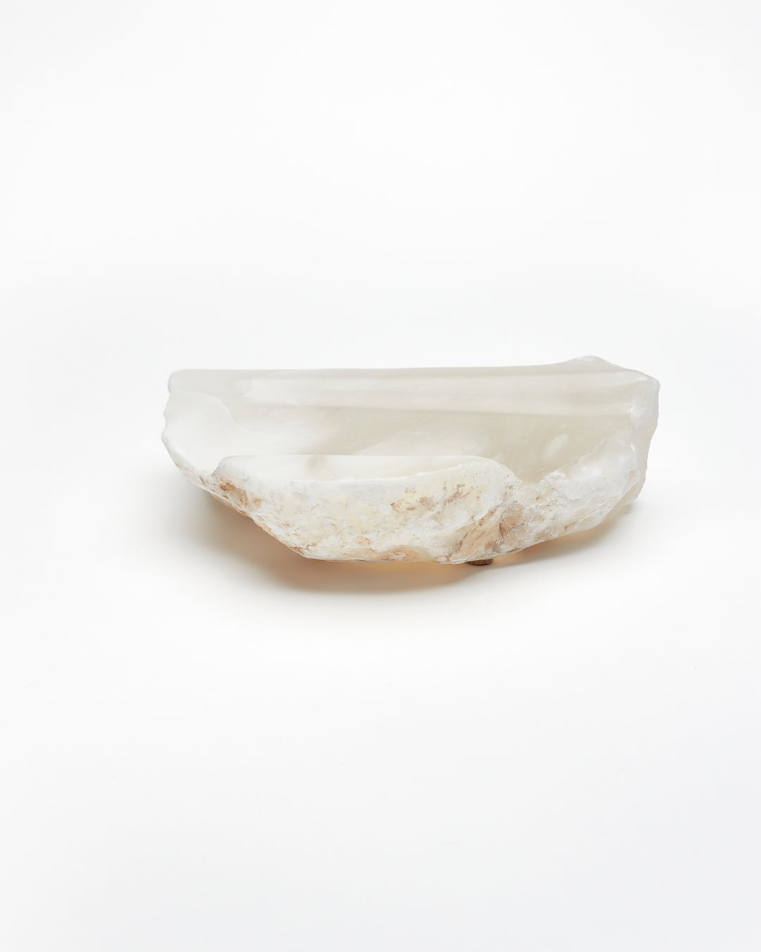 Side view: white translucent alabaster tray with brown flecks, raw and smooth edges.