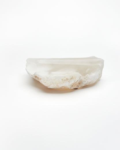 Side view: white translucent alabaster tray with brown flecks, raw and smooth edges.