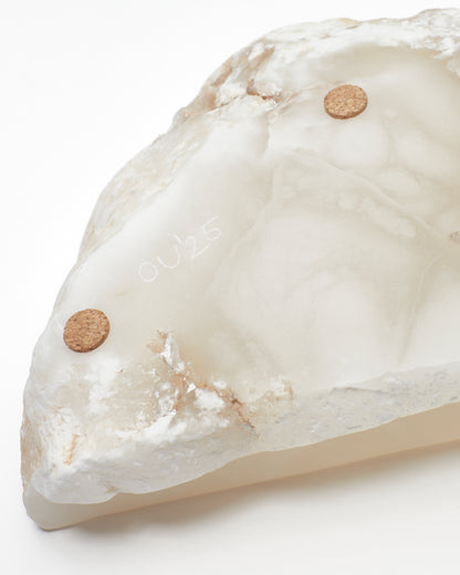 Underside close-up view: white translucent alabaster tray with flecks, cork pads, OU’25 engraving.