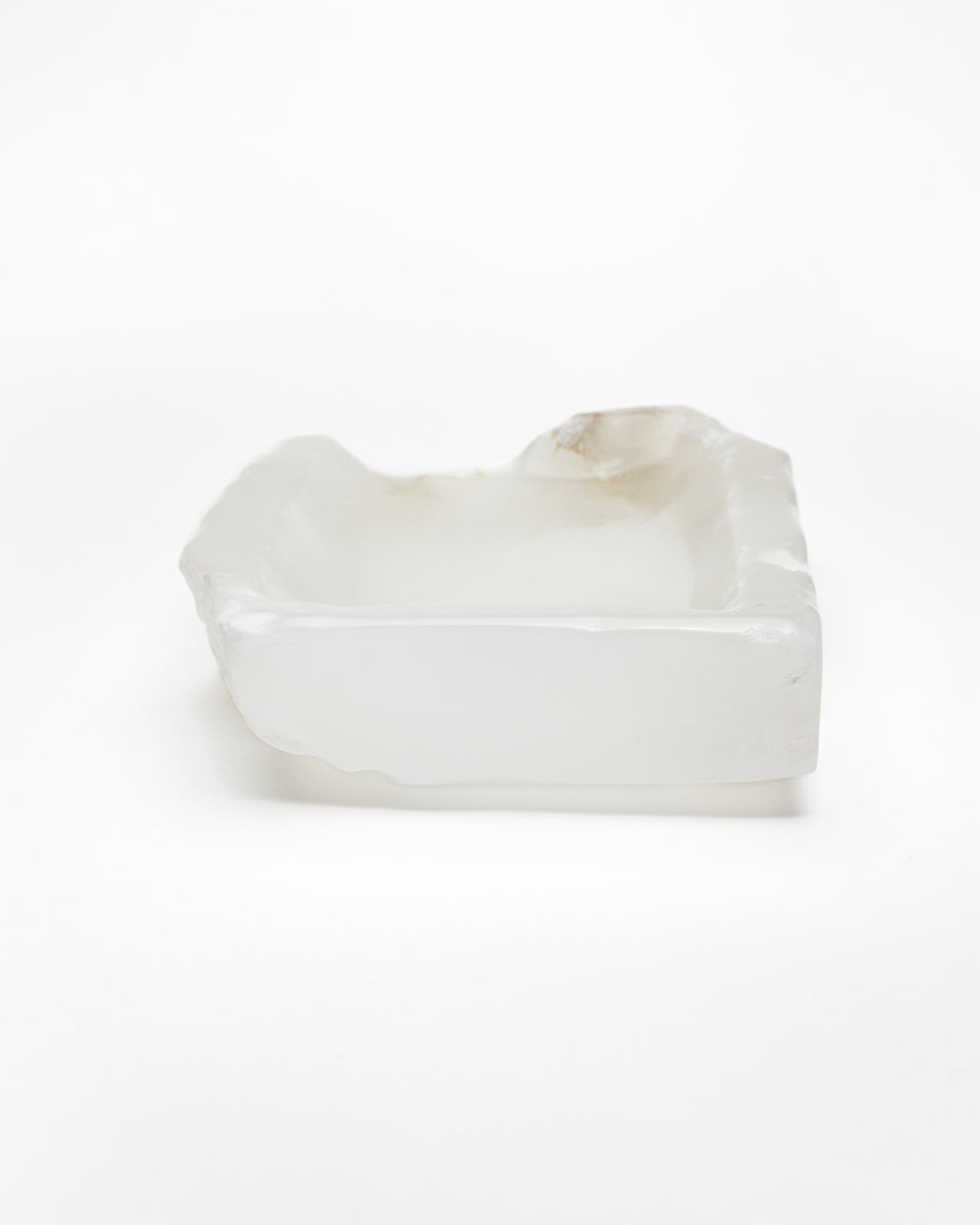 Back view: white translucent alabaster tray with raw and smooth edges and subtle brown veining.