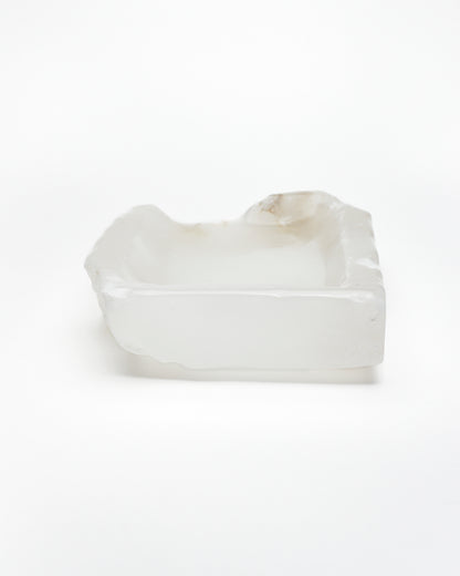 Back view: white translucent alabaster tray with raw and smooth edges and subtle brown veining.