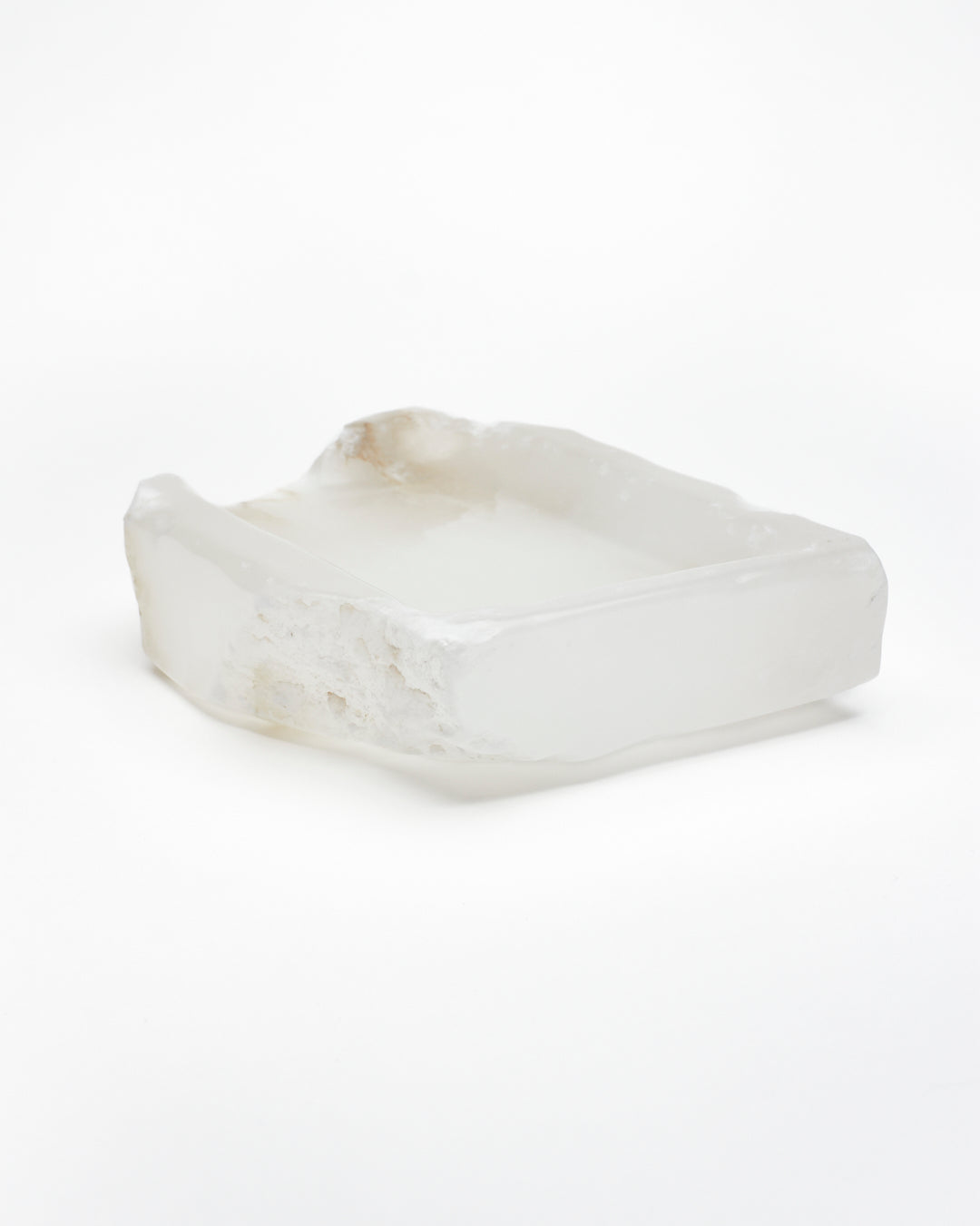 Angled back: white translucent alabaster tray with raw and smooth edges, subtle veining.