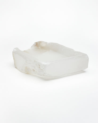 Angled back: white translucent alabaster tray with raw and smooth edges, subtle veining.