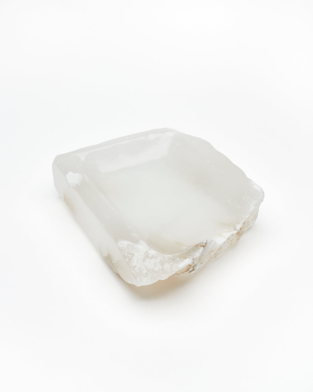 Angled view: white translucent alabaster tray with raw and smooth edges, subtle veining.