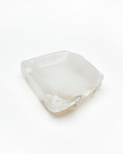 Angled view: white translucent alabaster tray with raw and smooth edges, subtle veining.