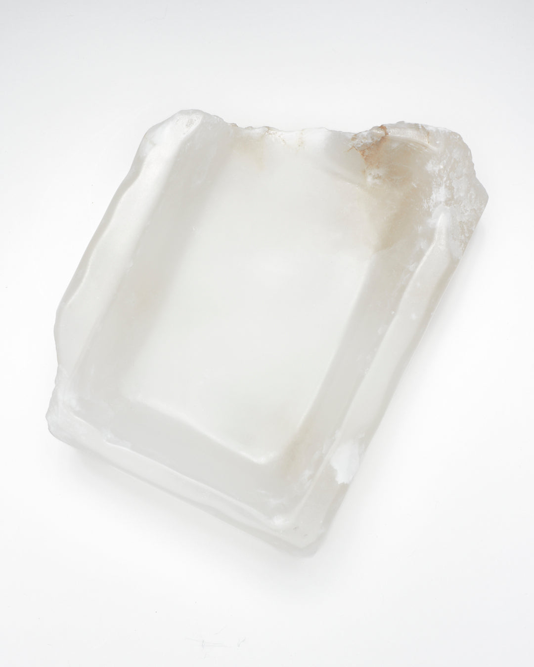 Top-down view: white translucent alabaster tray with raw and smooth edges, subtle veining.
