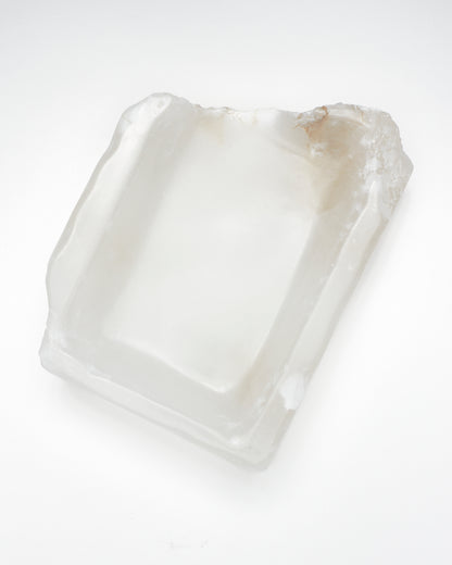 Top-down view: white translucent alabaster tray with raw and smooth edges, subtle veining.