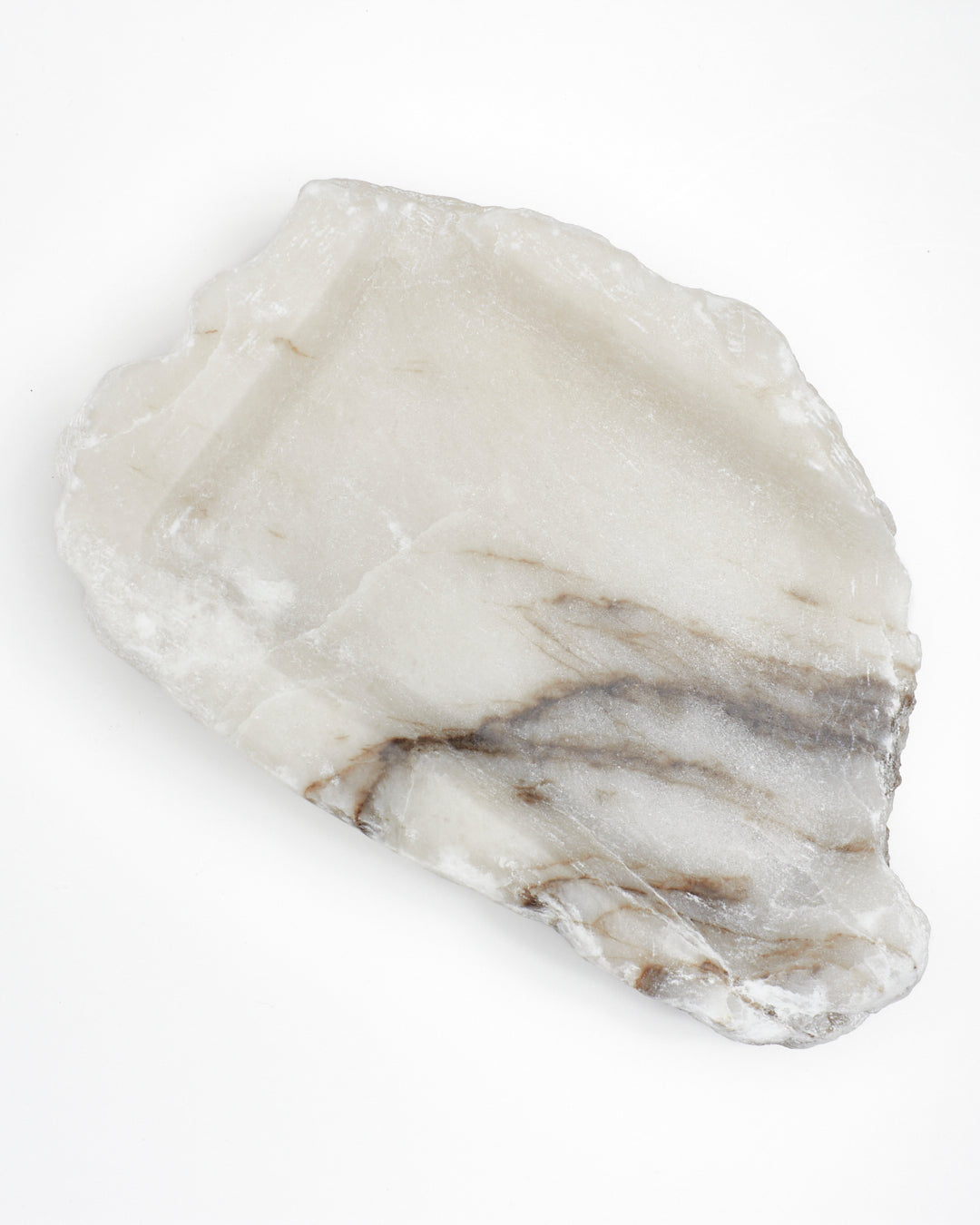 Top-down view: organic-shaped white alabaster tray, dark streaks, and raw edges.