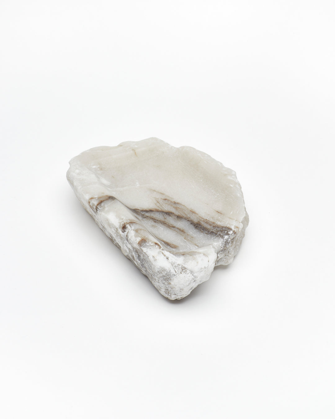 Angled view: organic-shaped white alabaster tray, dark streaks, and raw edges.