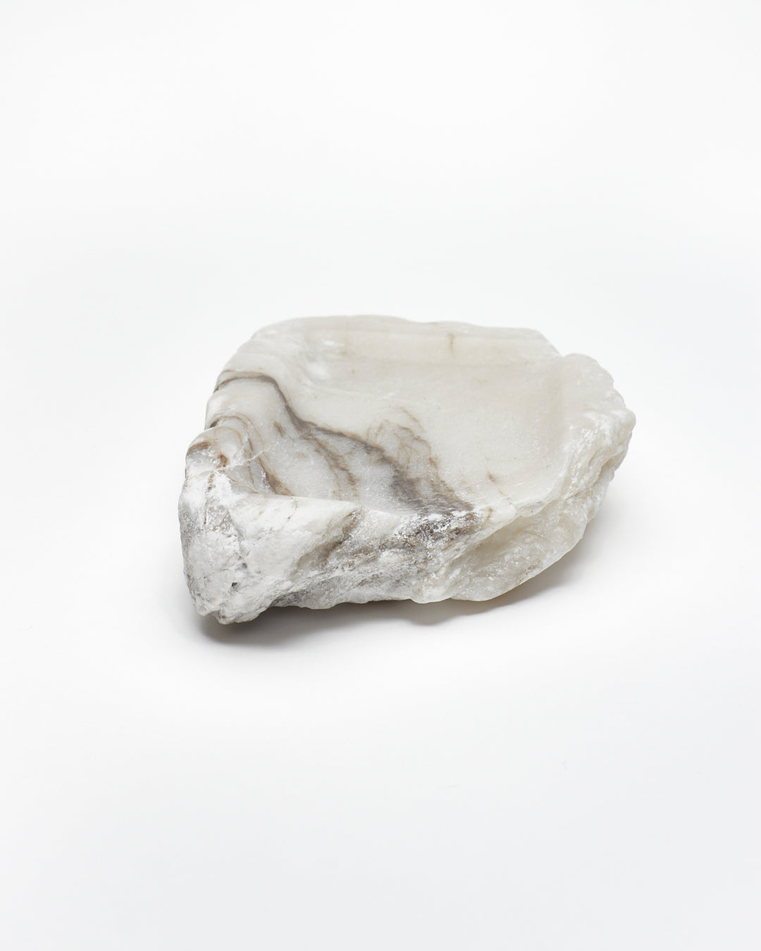 Front-on view: organic-shaped white alabaster tray, dark streaks, and raw edges.