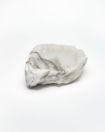 Front-on view: organic-shaped white alabaster tray, dark streaks, and raw edges.