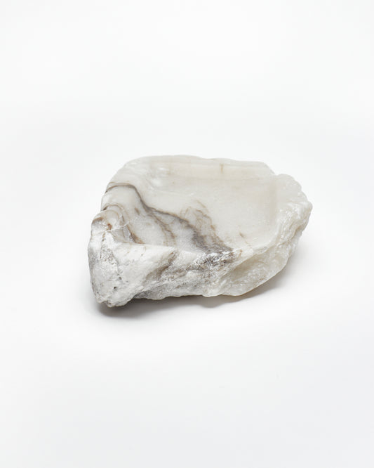Front-on view: organic-shaped white alabaster tray, dark streaks, and raw edges.