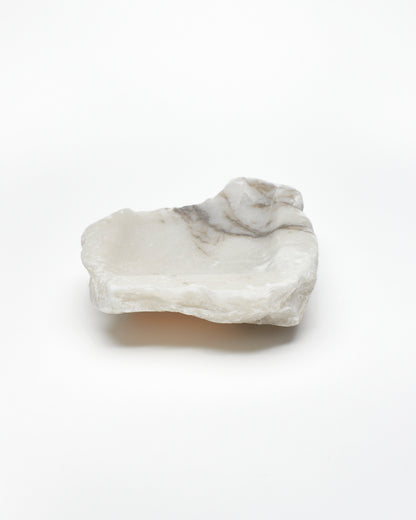 Back view: organic-shaped white alabaster tray, dark streaks, and raw edges.