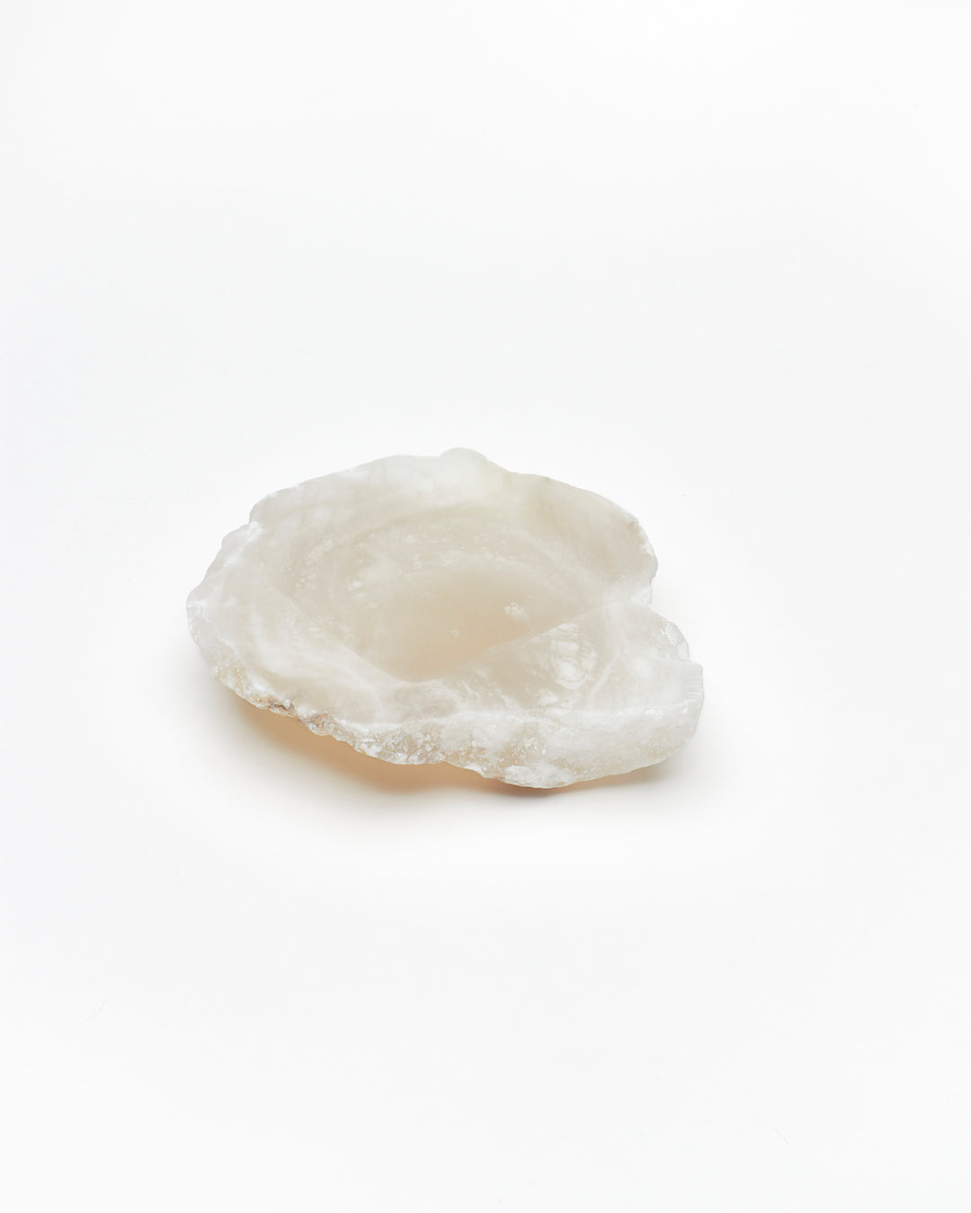 Angled view: organic-shaped white translucent alabaster tray, brown flecks, and raw edges.