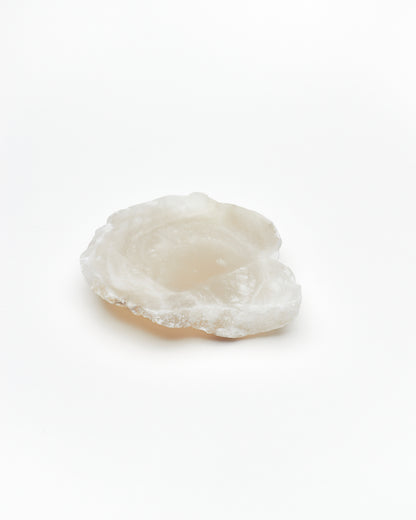 Angled view: organic-shaped white translucent alabaster tray, brown flecks, and raw edges.