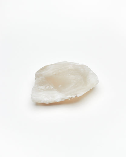 Angled view: organic-shaped white translucent alabaster tray, brown flecks, and raw edges.