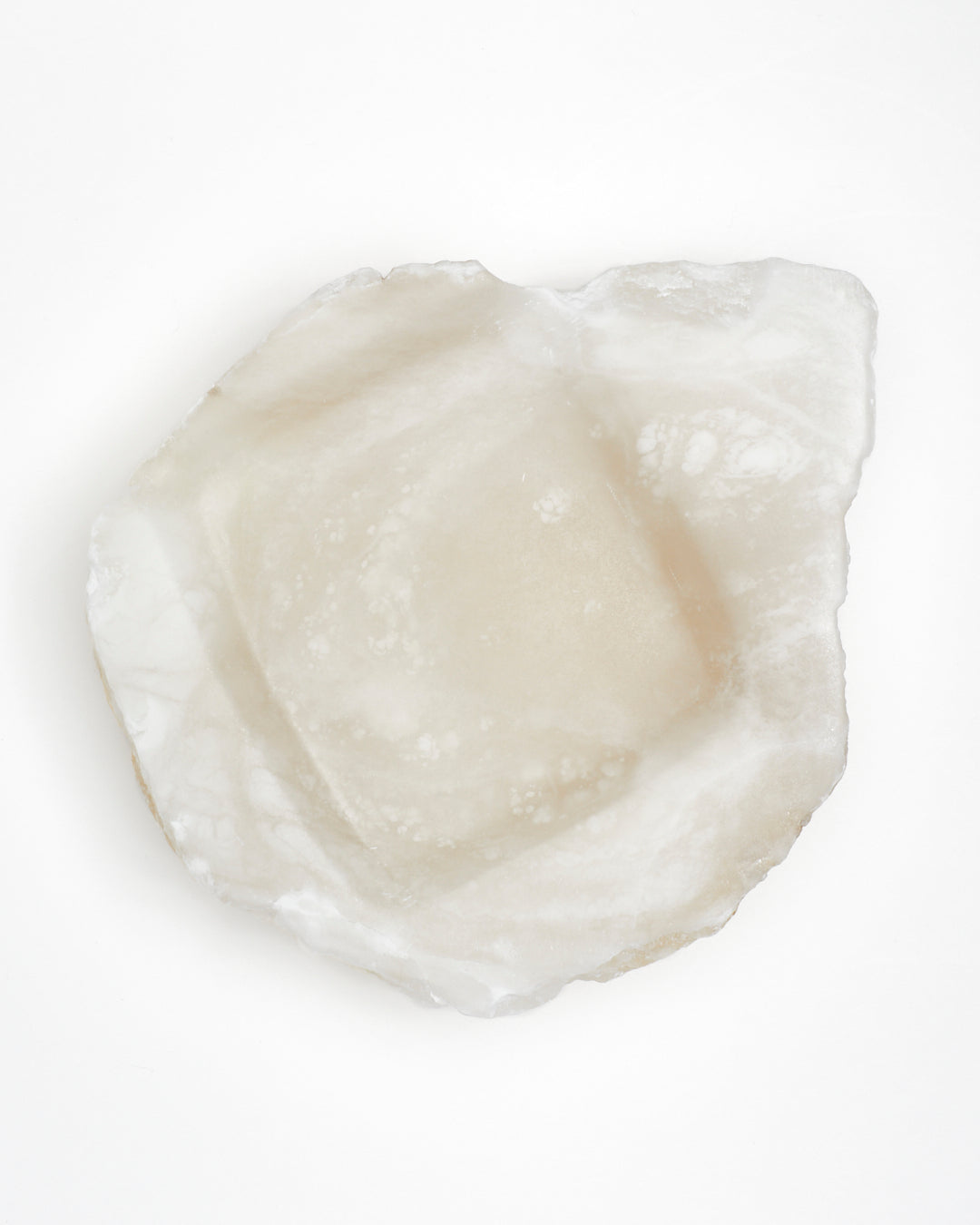 Top-down view: organically shaped, white translucent alabaster tray with raw edges.