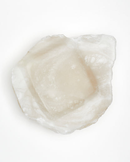Top-down view: organically shaped, white translucent alabaster tray with raw edges.