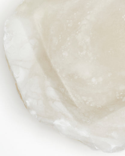 Top-down close-up: organically shaped, white translucent alabaster surface with raw edges.