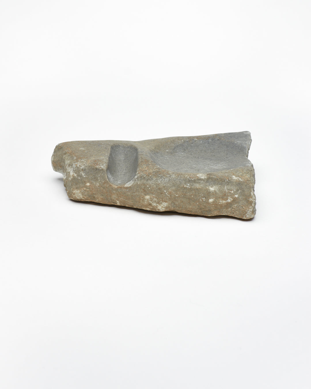 Side view: organic-shaped gray-brown stone sculpture, raw edges, round and oval carvings.