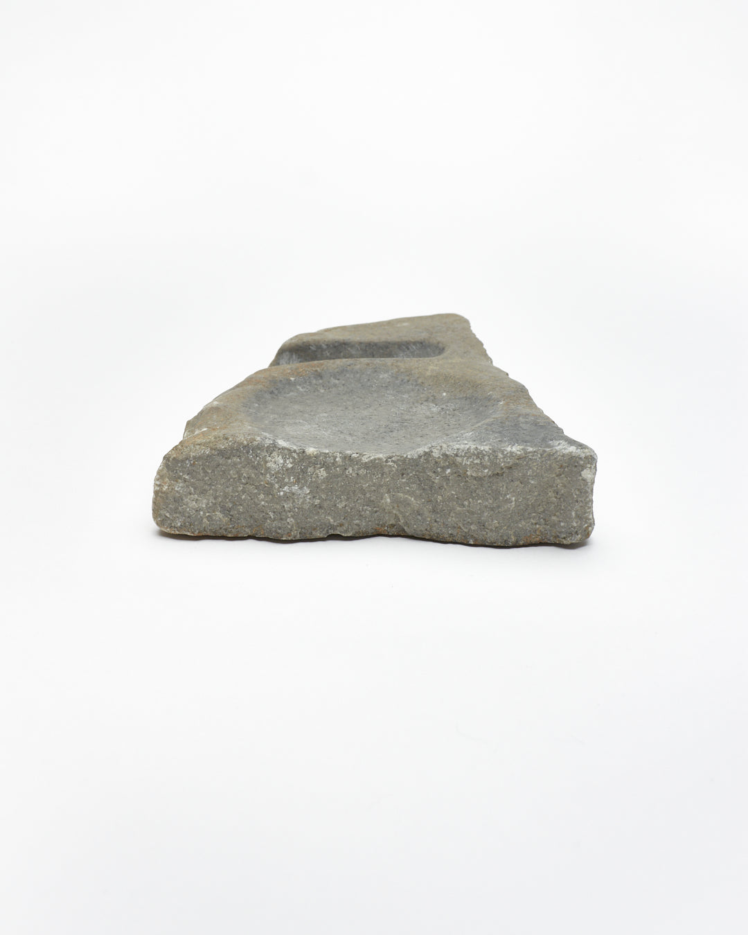 Back view: organic-shaped gray stone sculpture, raw edges, round and oval carvings.