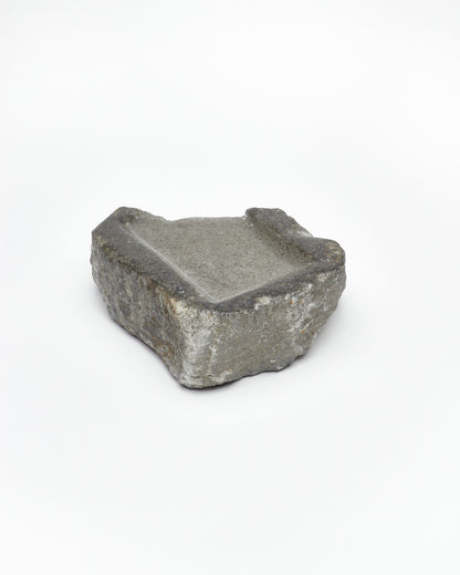 Angled back view: organic-rectangle-shaped gray stone tray with raw edges.