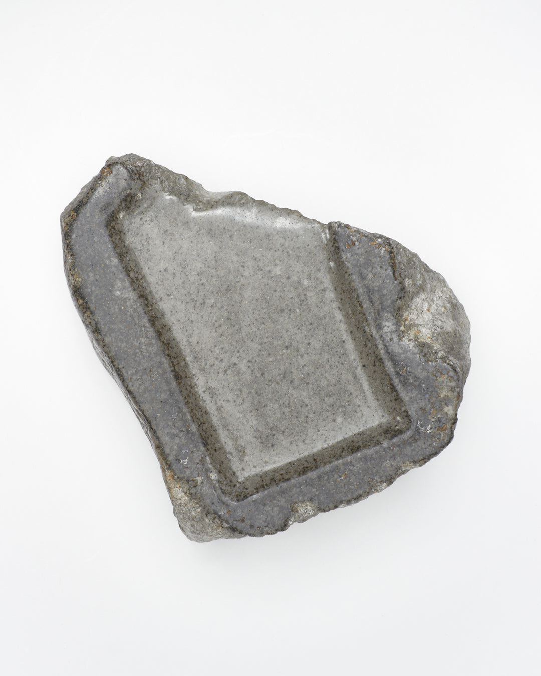 Top-down view: organic-rectangle-shaped gray stone tray with raw edges and a smooth surface.