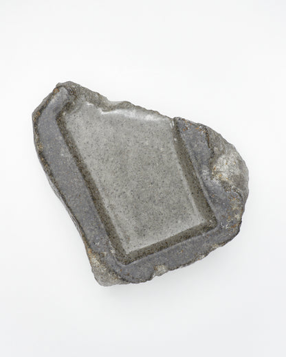 Top-down view: organic-rectangle-shaped gray stone tray with raw edges and a smooth surface.