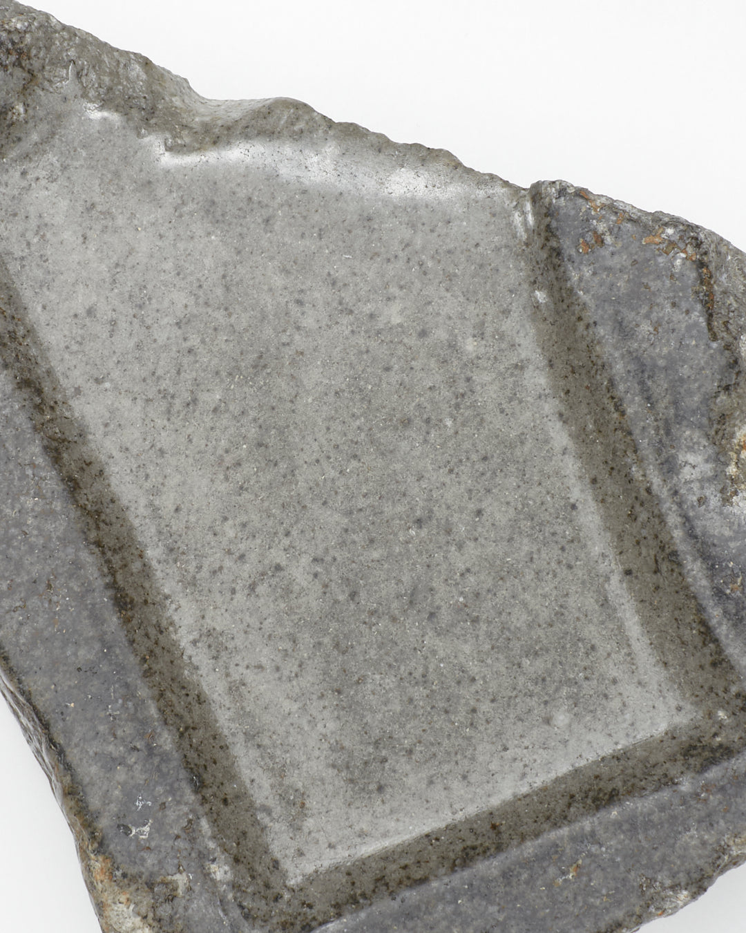 Top-down close-up: organic-shaped, gray stone tray with raw edges and a smooth surface.