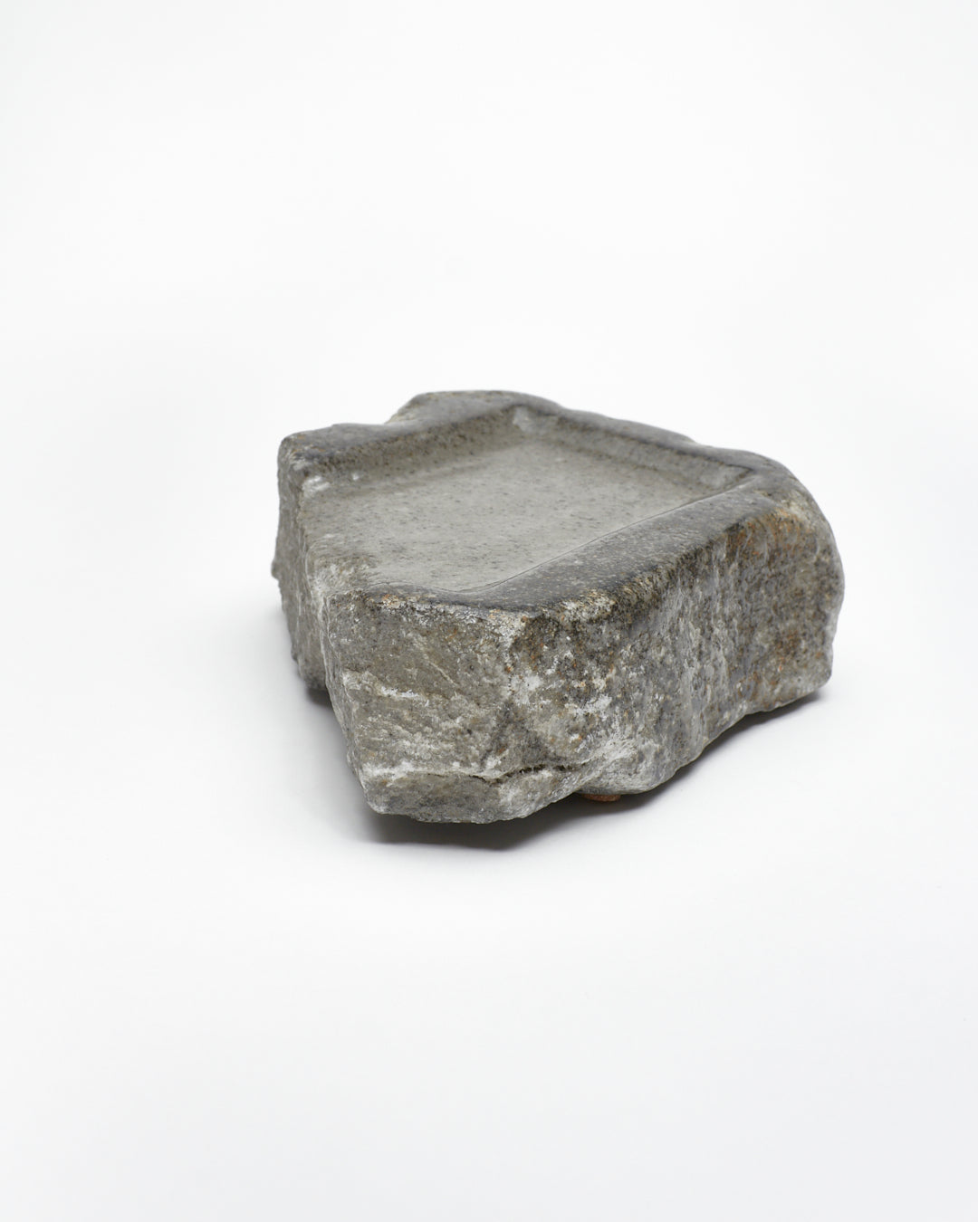Angled view: organic-rectangle-shaped gray stone tray with raw edges.