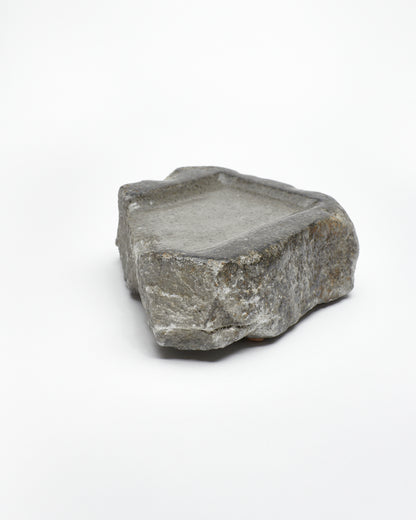 Angled view: organic-rectangle-shaped gray stone tray with raw edges.