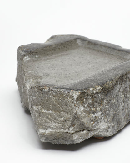 Angled close-up view: organic-rectangle-shaped gray stone tray with raw edges.