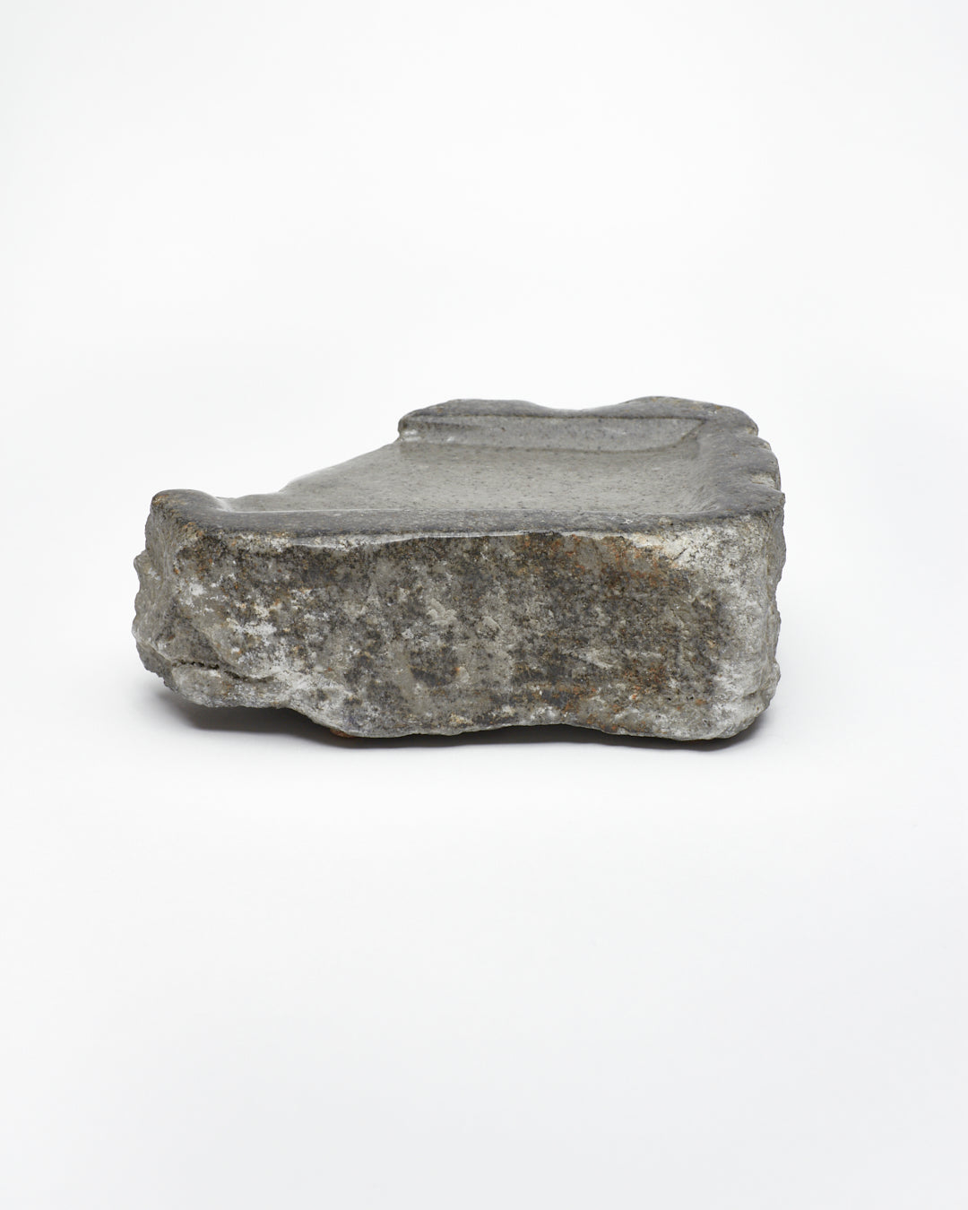 Side view: organic-rectangle-shaped gray stone tray with raw edges.
