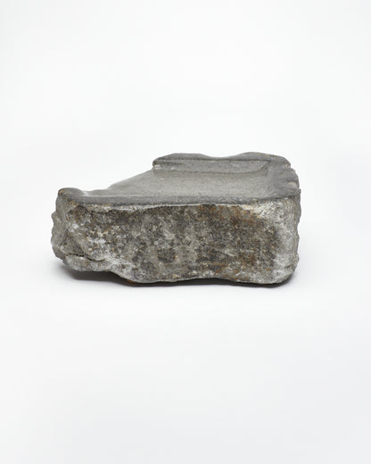 Side view: organic-rectangle-shaped gray stone tray with raw edges.