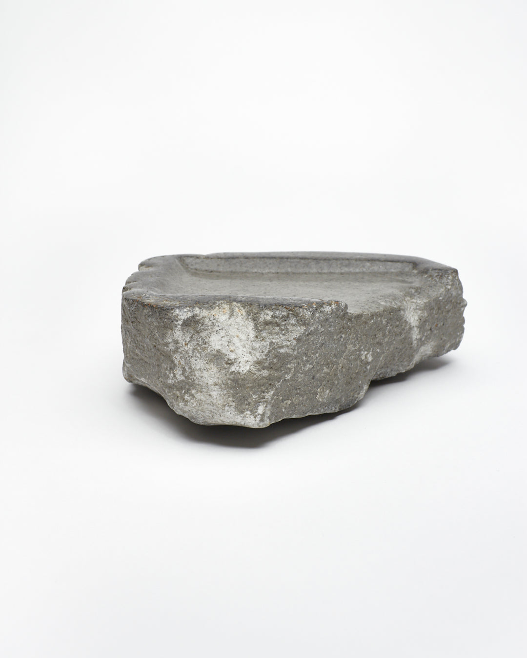 Side view: organic-rectangle-shaped gray stone tray with raw edges.