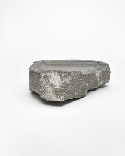 Side view: organic-rectangle-shaped gray stone tray with raw edges.